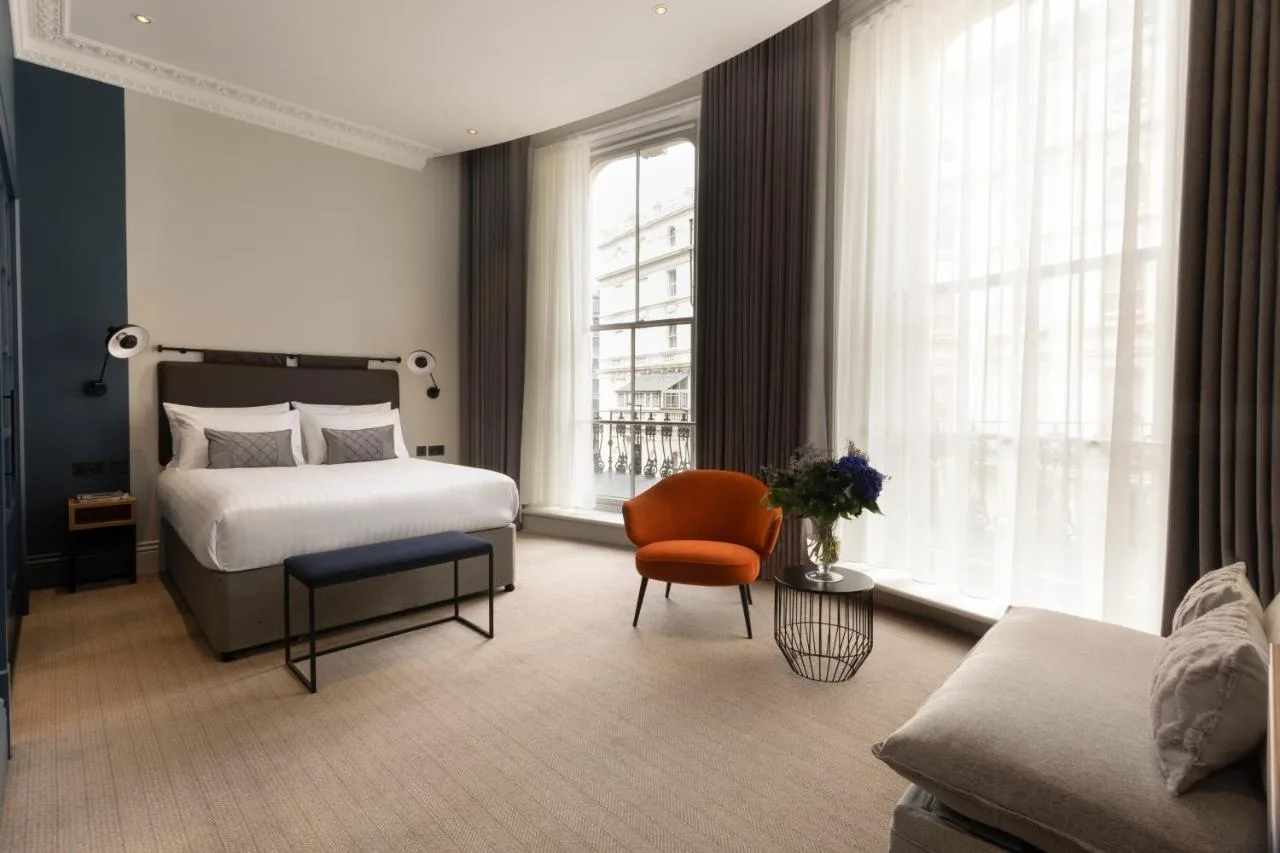 a bedroom with a bed and a chair and a couch at The 55 by Le Mirage in London