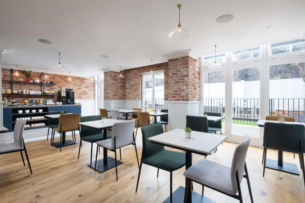 a restaurant with tables and chairs and windows at The 55 by Le Mirage in London