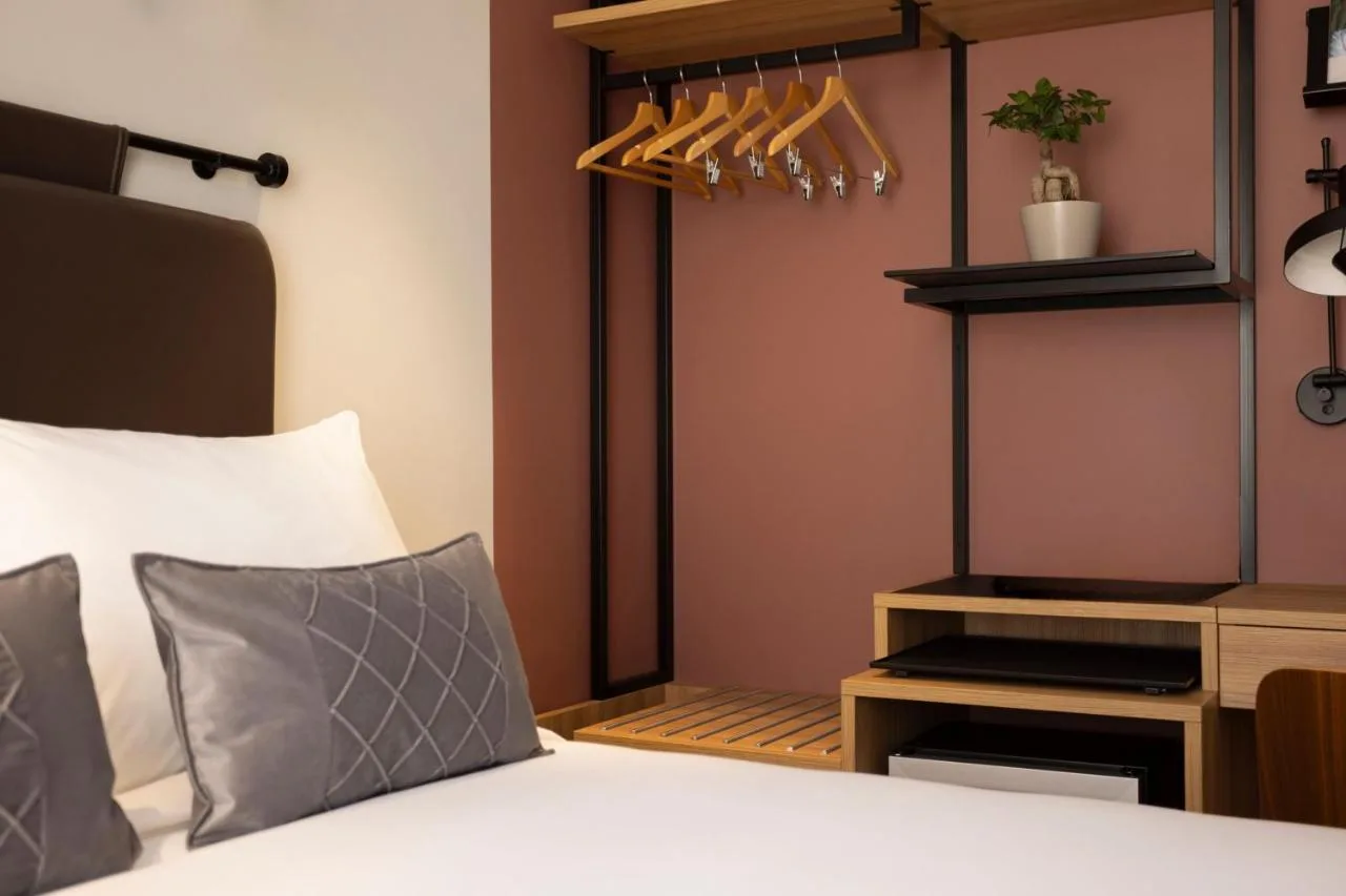 a bedroom with a bed and a shelf with hangers at The 55 by Le Mirage in London