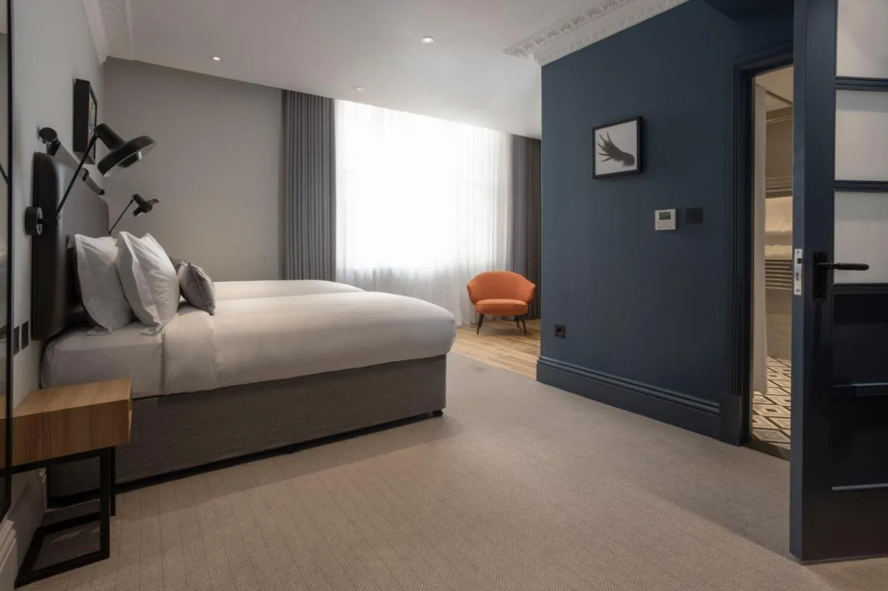 a bedroom with a bed and a blue wall at The 55 by Le Mirage in London